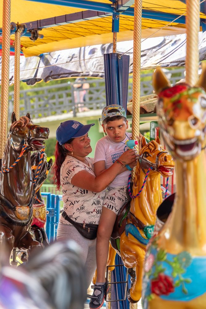 Una mamá y su hijo montan juntos en el carrusel del Parque del Café