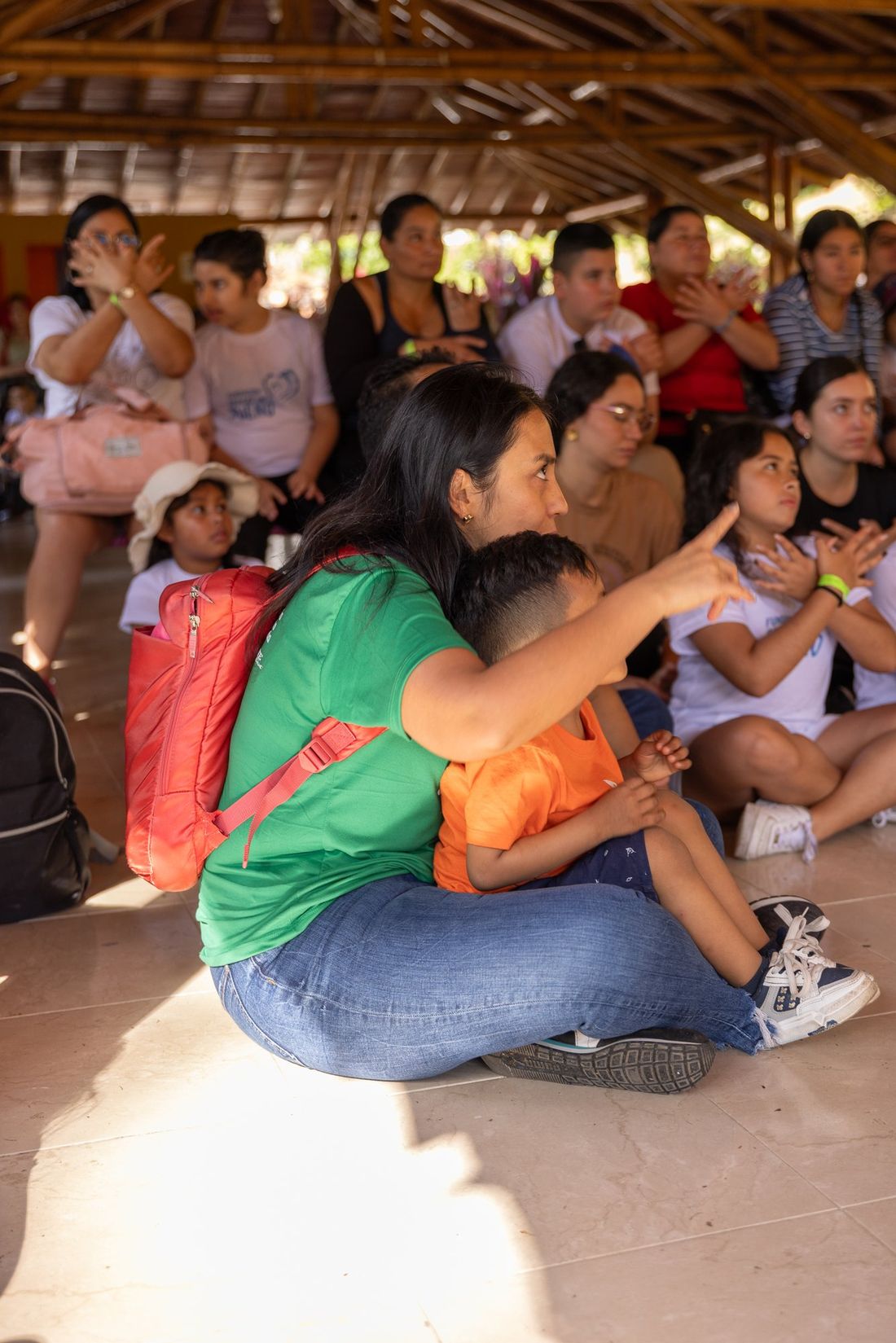 Una mamá y su hijo, sentados entre los demás niños, durante la celebración de Navidad del viaje 2025
