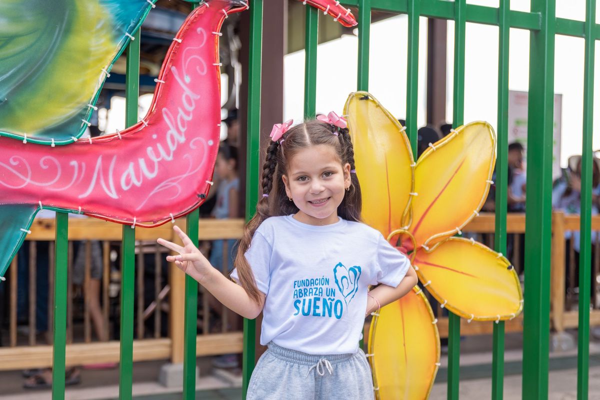 Una niña sonríe junto a un letrero de Navidad