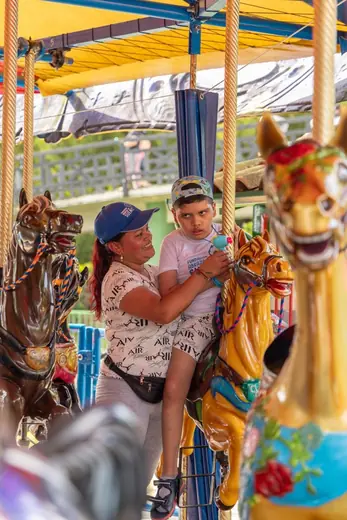 Una mamá y su hijo montan juntos en el carrusel del Parque del Café