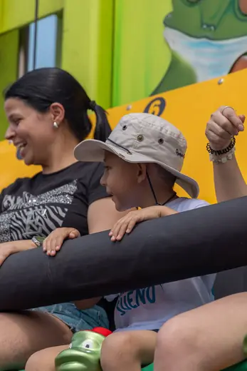 Un niño ríe en una atracción junto a su mamá