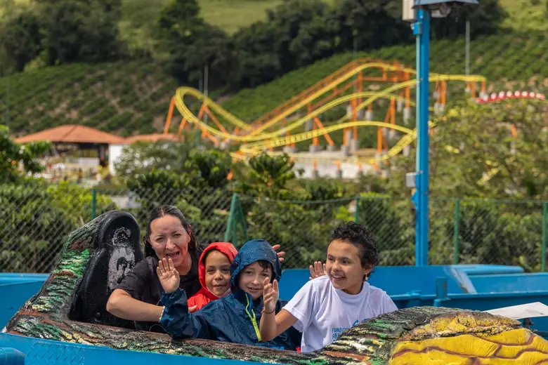 Niños saludan sonrientes desde el carrito de la montaña rusa